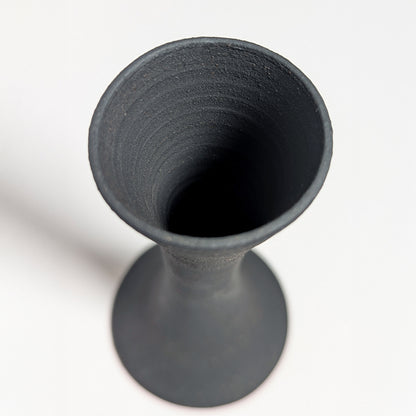 Looking down into the open mouth of the black clay candle holder, the interior reveals smooth throwing lines and a deep matte finish with natural texture variations.
