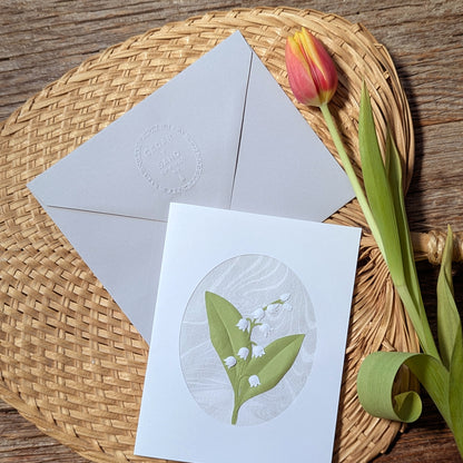Lily of the valley notecard styled with tulip and woven tray, featuring marbled background and sculpted paper floral design