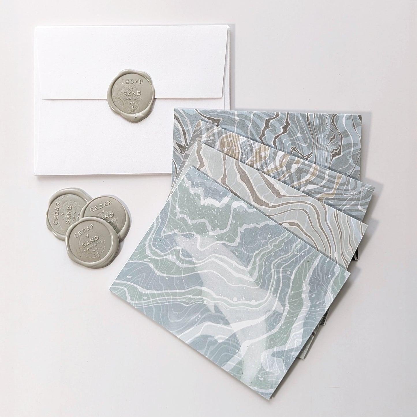 Marine Fauna Fin Series notecards displayed with white envelopes and gray Cedar Y Sand insignia self-adhesive wax seals.
