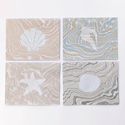 Set of four Marine Fauna Suminagashi notecards featuring scallop, whelk, starfish, and clam designs with hand-marbled suminagashi backgrounds.