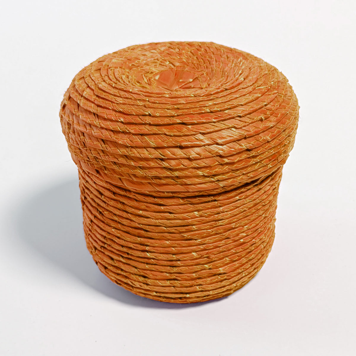 Lidded pumpkin-orange palm leaf woven basket, on a white surface.