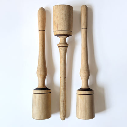 Three wooden narrow pestles tools with  varied accents on a white background