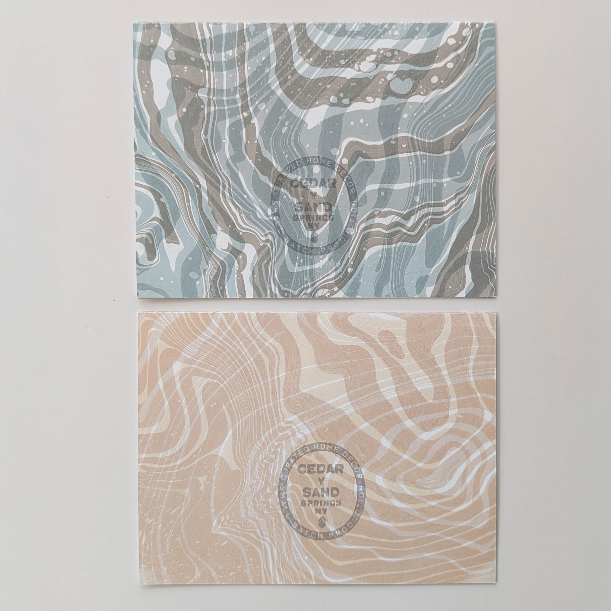 Back of Moonset and Sunrise Suminagashi notecards featuring flowing marbled designs and gray-stamped CEDAR Y SAND insignia.