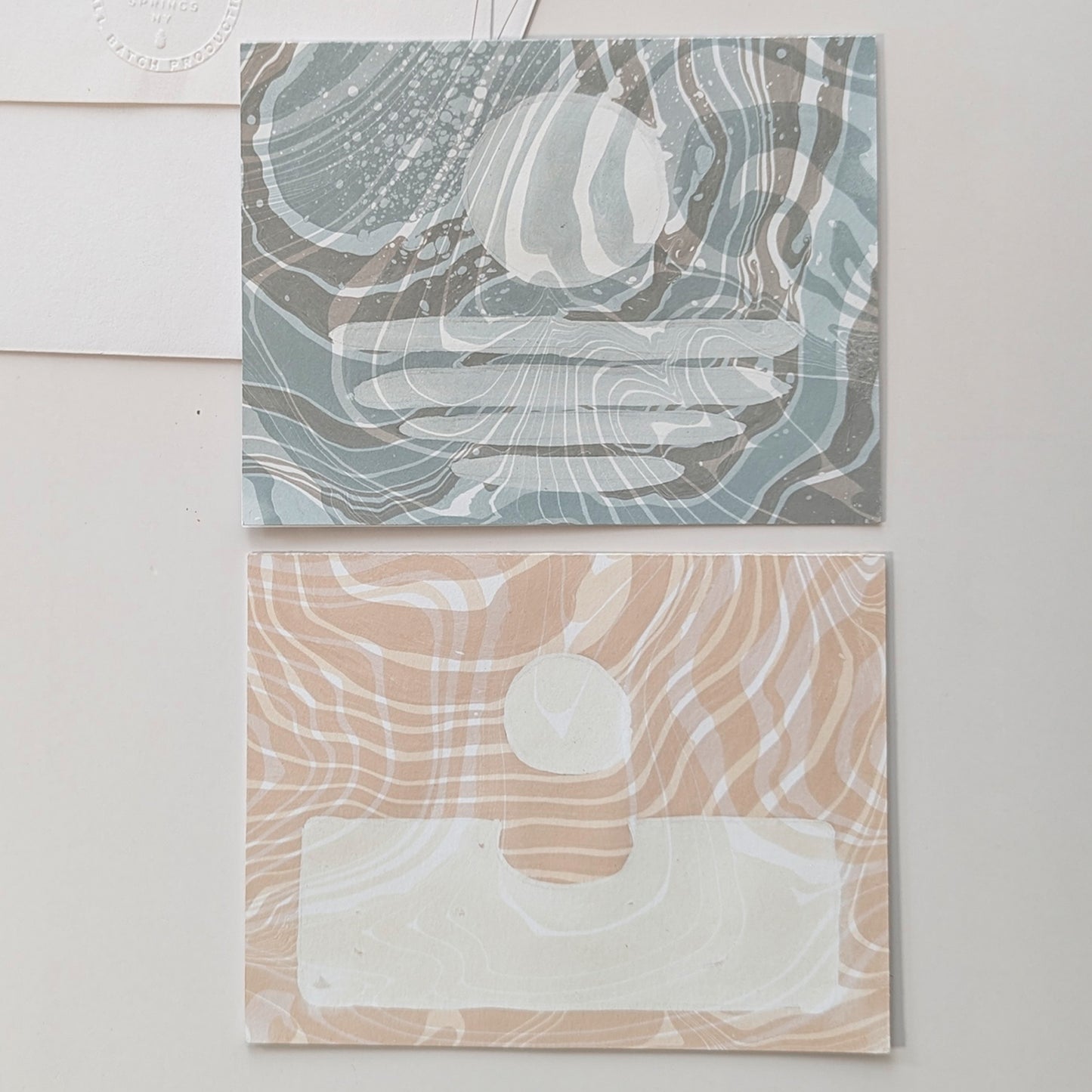 Close-up of Moonset and Sunrise Suminagashi notecards showing marbled textures and celestial masking details.