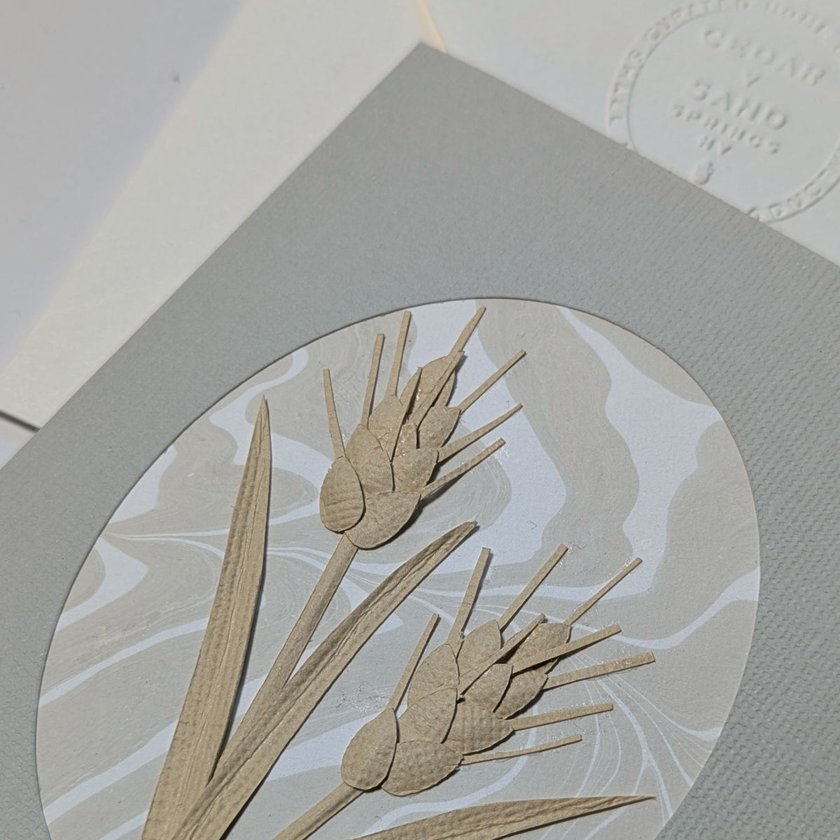 Close-up of hand-cut and sculpted paper wheat layered over neutral Suminagashi marbling on the Wheat Paper Botanicals notecard.
