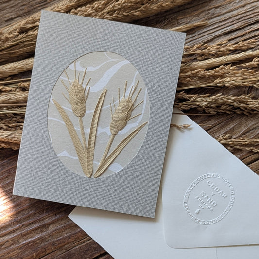 Handmade Wheat Suminagashi notecard styled among dried wheat, featuring dimensional hand-cut paper botanicals by CEDAR Y SAND.