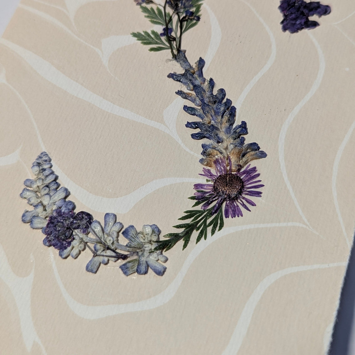 Pressed floral “S” initial notecard with blue and pink flowers on marbled Suminagashi background, handmade on Fabriano Medioevalis paper