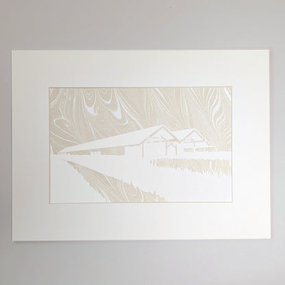 Golden-beige suminagashi marbled paper behind a hand-cut silhouette of the Parrish Art Museum, presented in a natural mat.