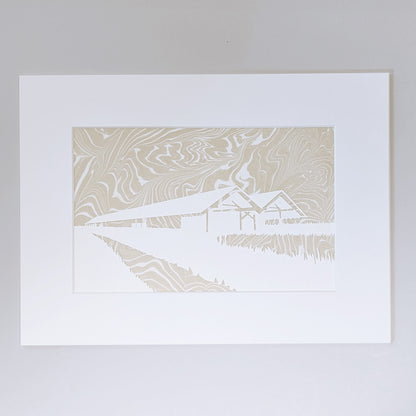 Paper cut silhouette of Parrish Art Museum over wheat-colored suminagashi marbled paper, matted in white.