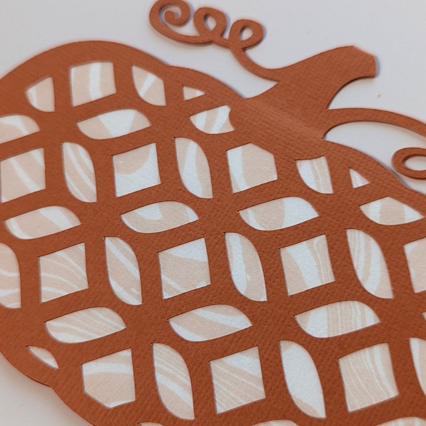 Close-up of Pumpkin Lattice Notecard showing marbled suminagashi paper through geometric cut-out pattern.