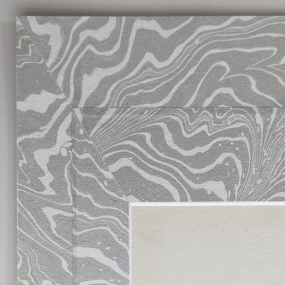 Close view of cool gray and off white suminagashi Hosho paper collaged mat surrounding painting.