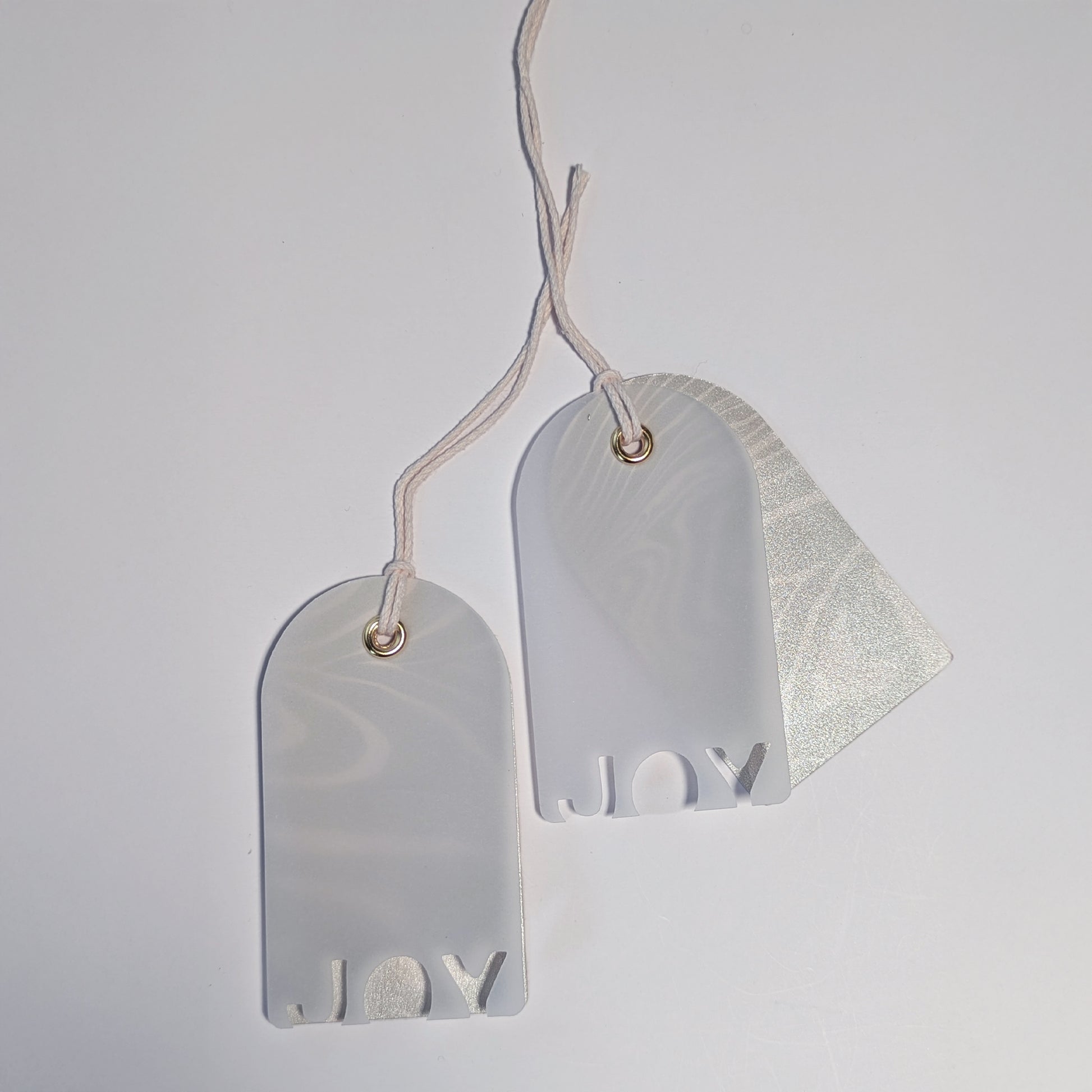 Two JOY vellum gift tags with pearlized Suminagashi marbled backings, shown as a matching pair with twine ties.