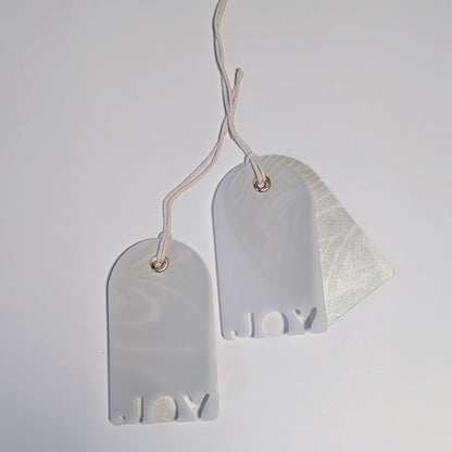 Two JOY vellum gift tags with pearlized Suminagashi marbled backings, shown as a matching pair with twine ties.