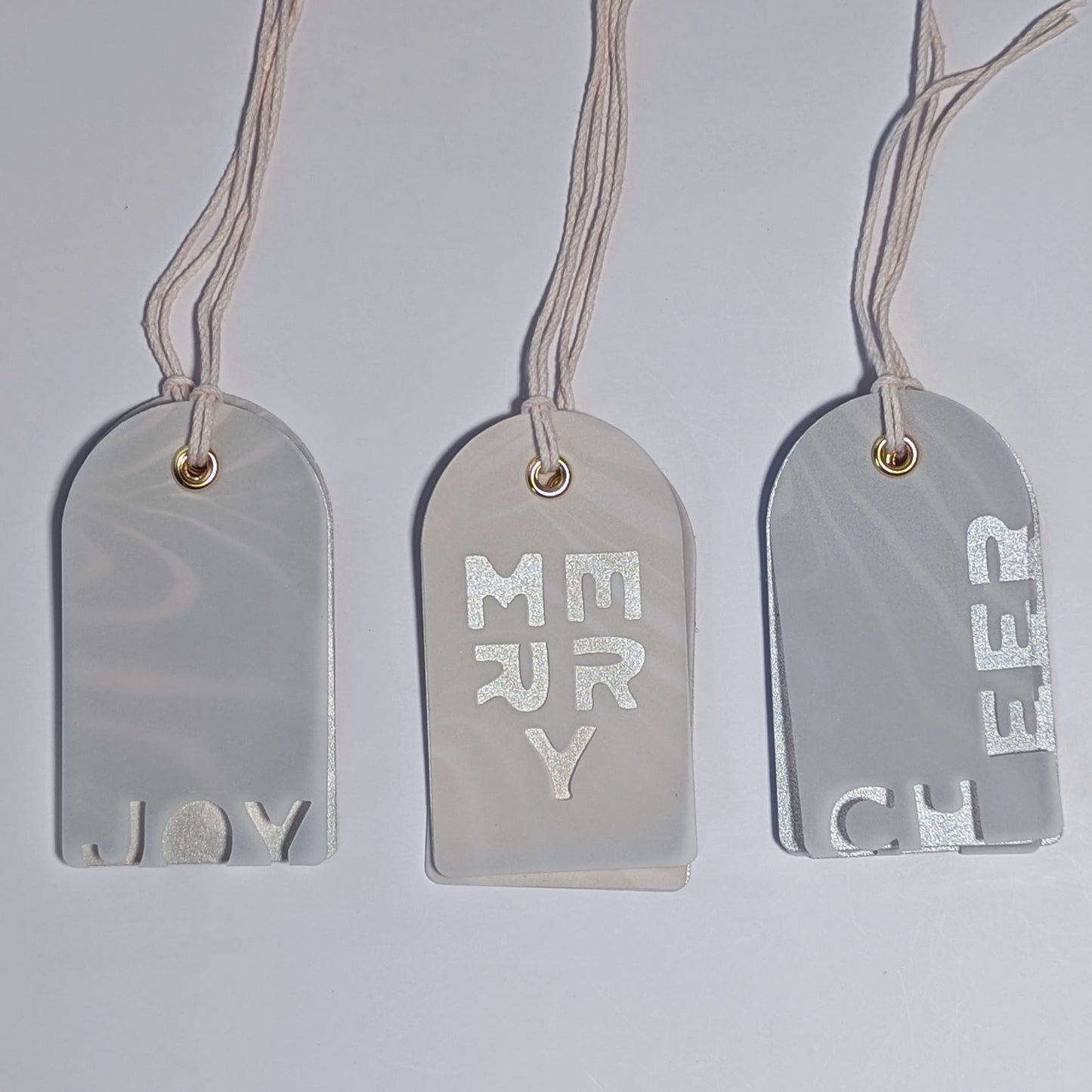 JOY, MERRY, and CHEER layered Suminagashi gift tags hanging by natural cotton twine, showing vellum overlay and marbled backing.