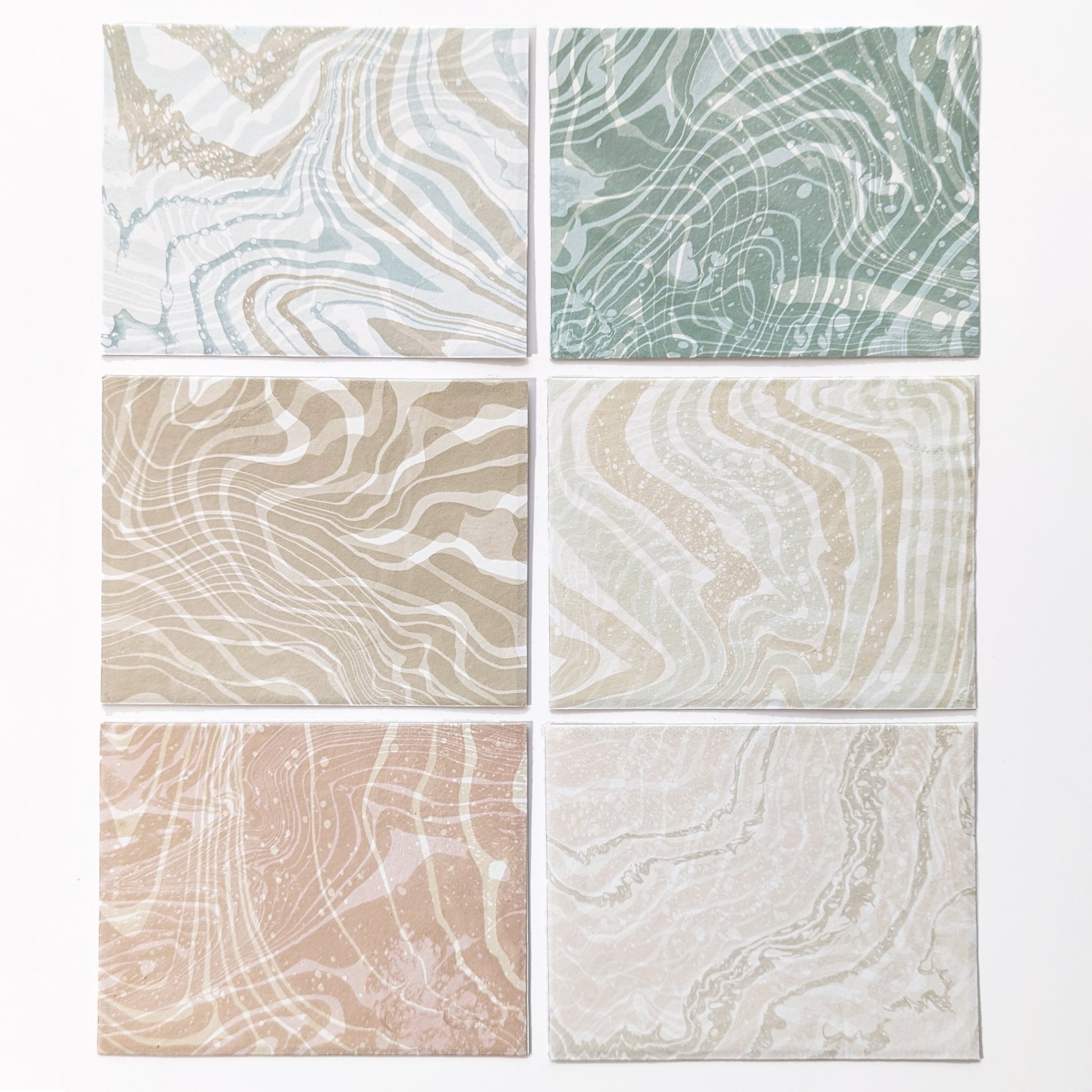 Six assorted Suminagashi Hosho notecards, marbled front and back, showing colorways Ditch Plains, Acabonac Harbor, Dunes, Walking Dunes, Sunset, and Scallop.