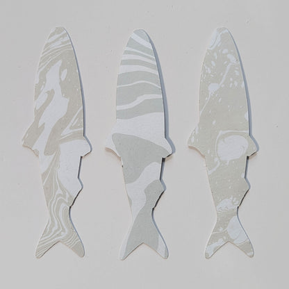 Reverse side of three handmade sardine bookmarks featuring unique muted neutral & gray hand-marbled Suminagashi paper patterns.