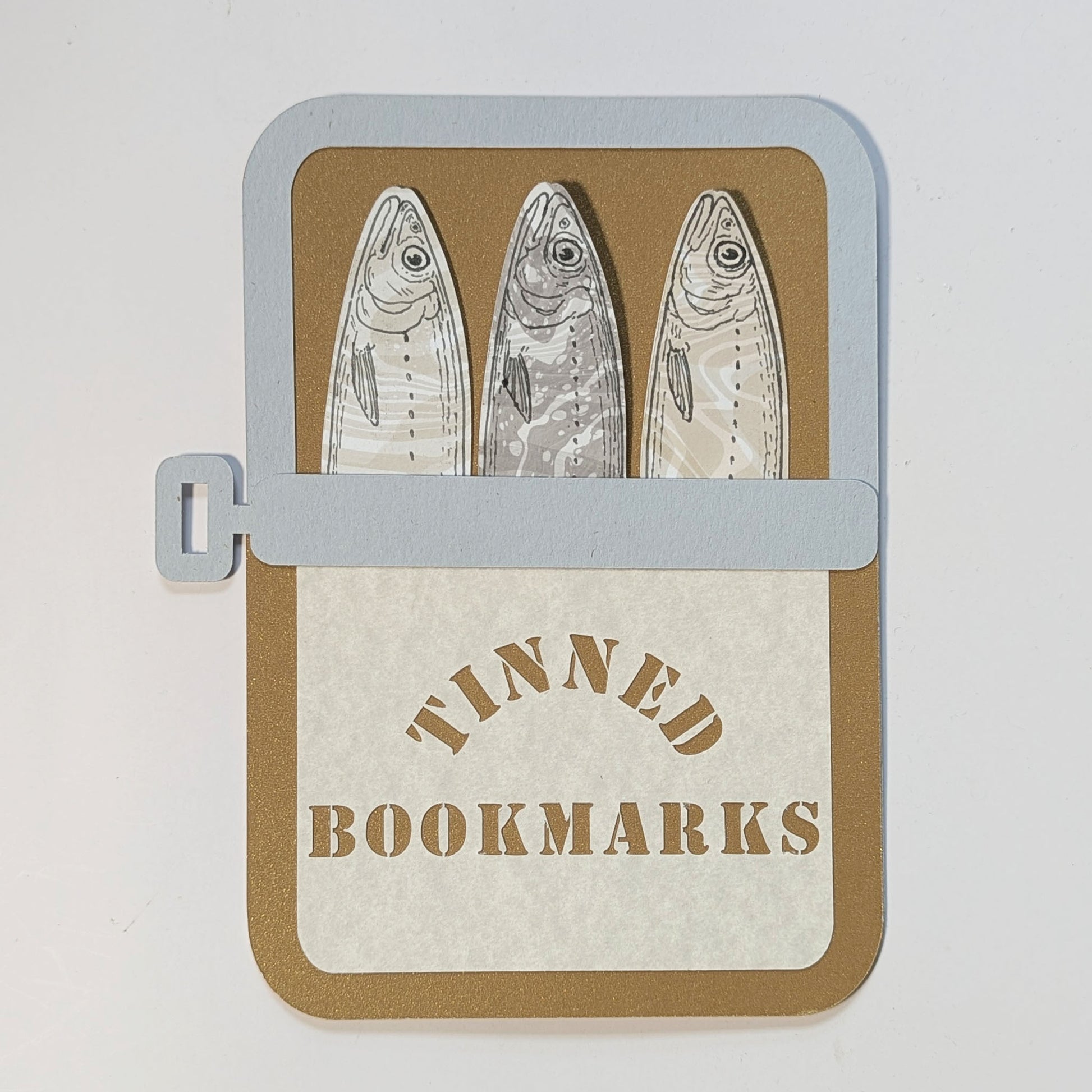 Handmade Tinned Sardines Bookmark Set with three die-cut sardine bookmarks packaged inside a custom paper sardine tin by CEDAR Y SAND.